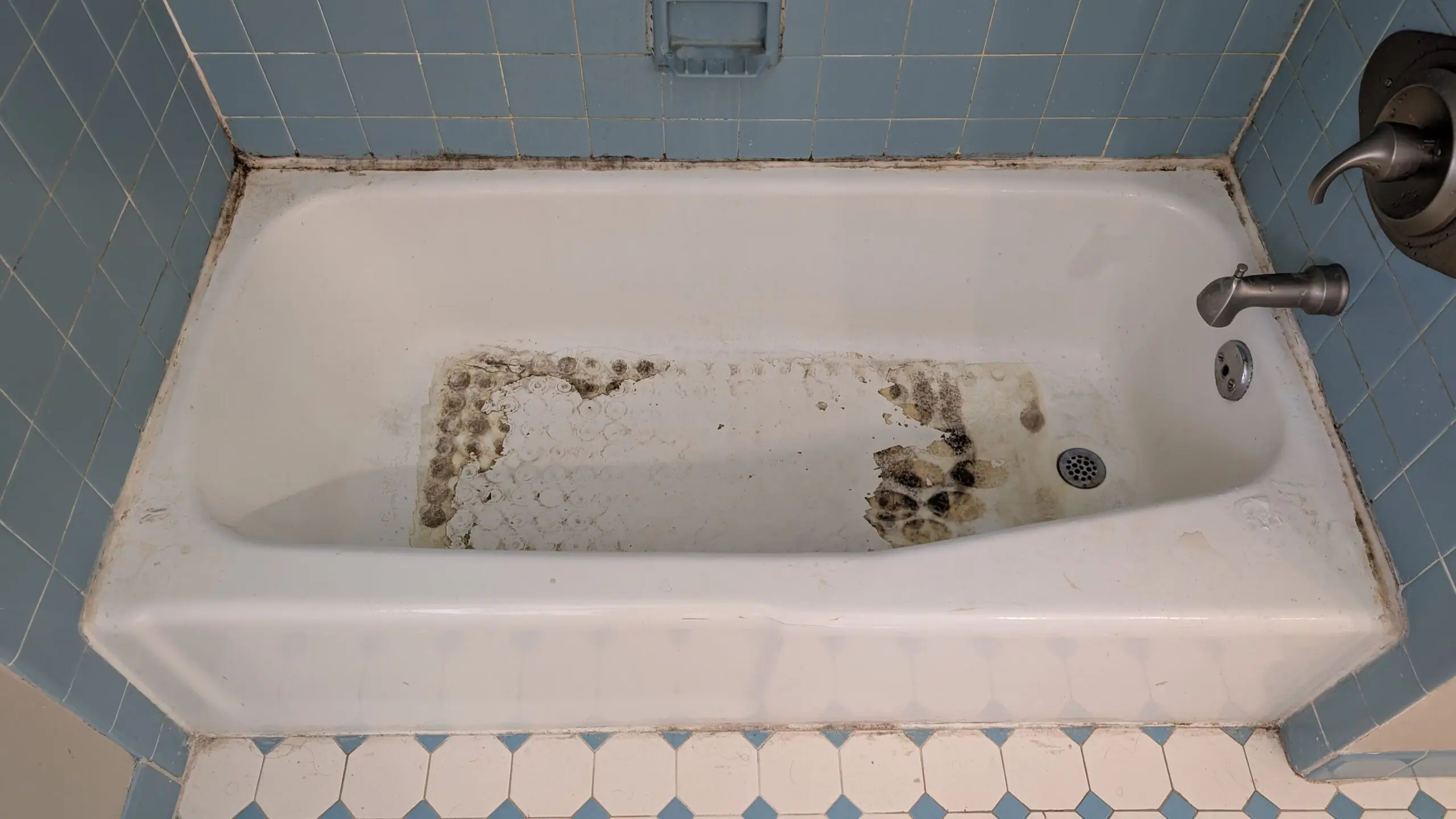 Dated bathtub with mold and stains in need of refinishing in NYC.
